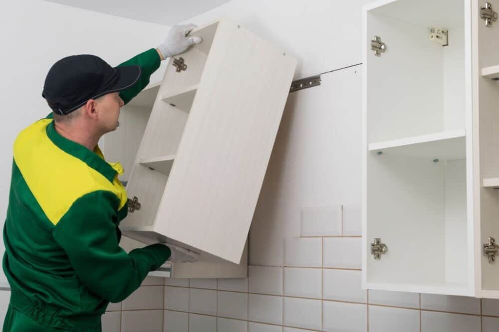 a worker hangs a kitchen cabinet on the wall